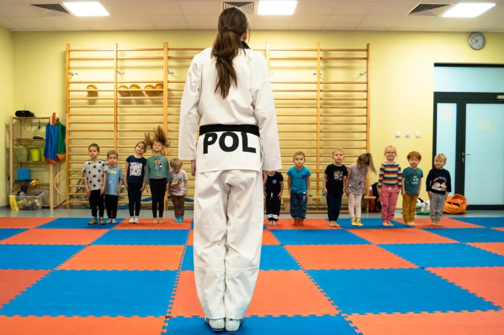 Instruktorka taekwondo prowadzi trening dla grupy małych dzieci w Akademii Taekwondo.